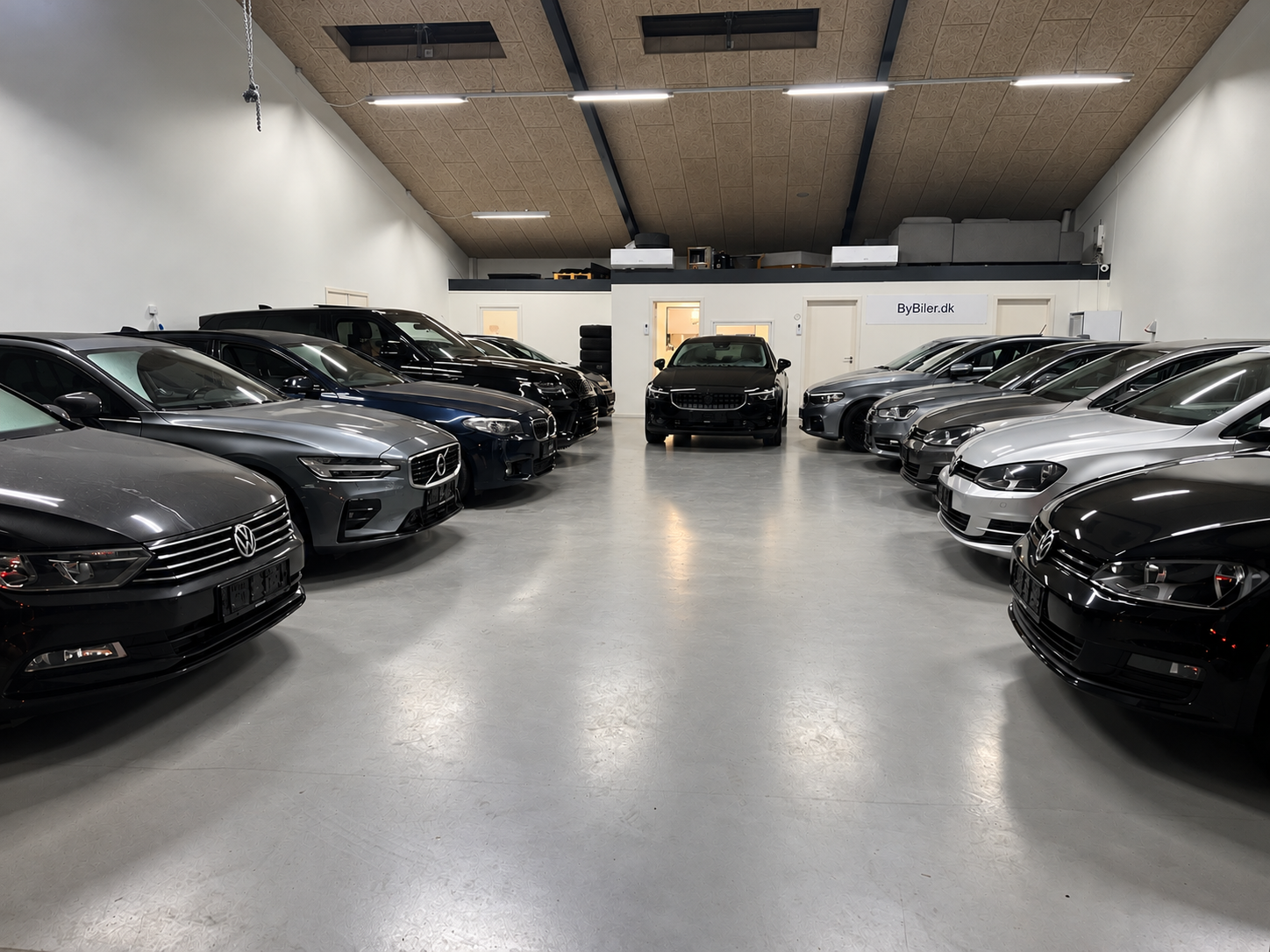 Overblik over ByBilers showroom med biler på begge sider